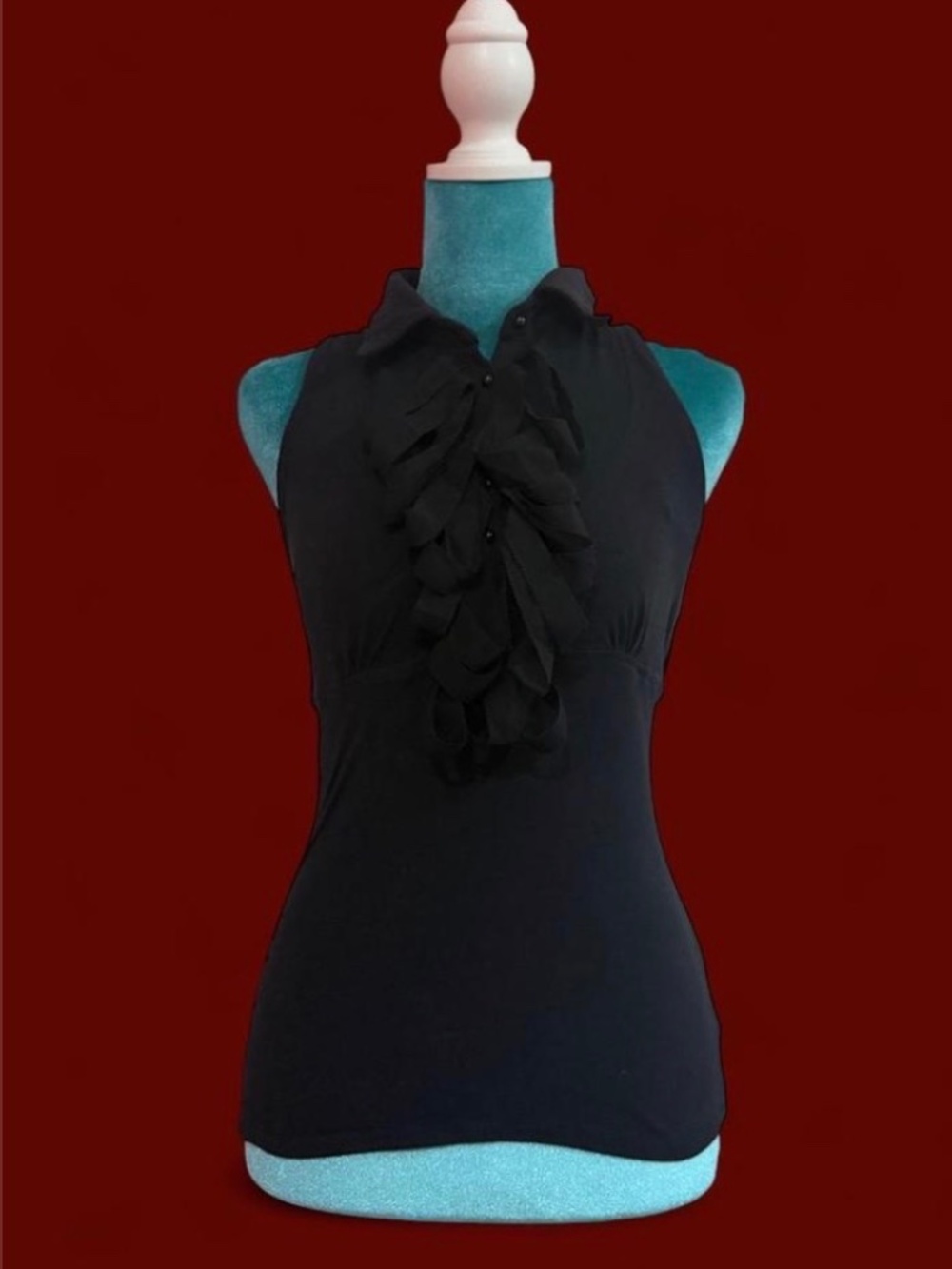 Beautiful Bebe sleeveless blouse featuring a dramatic cascading ruffle front